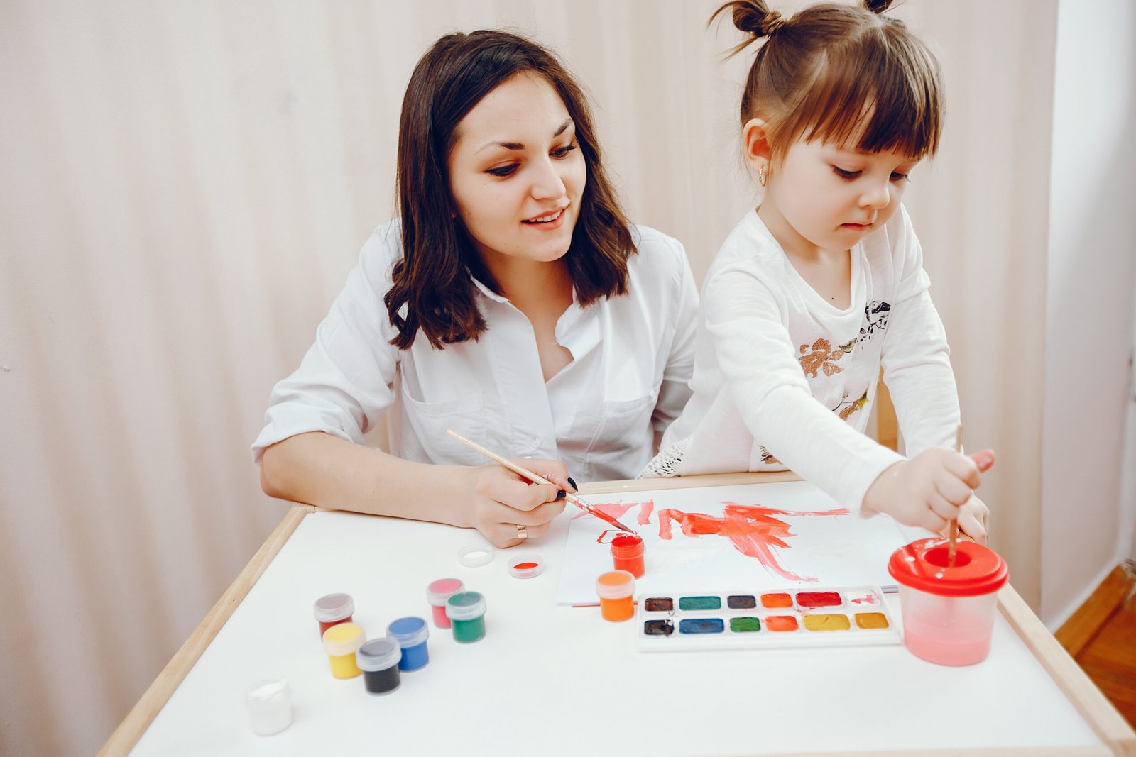 A young mother, along with her little daughter paints on paper